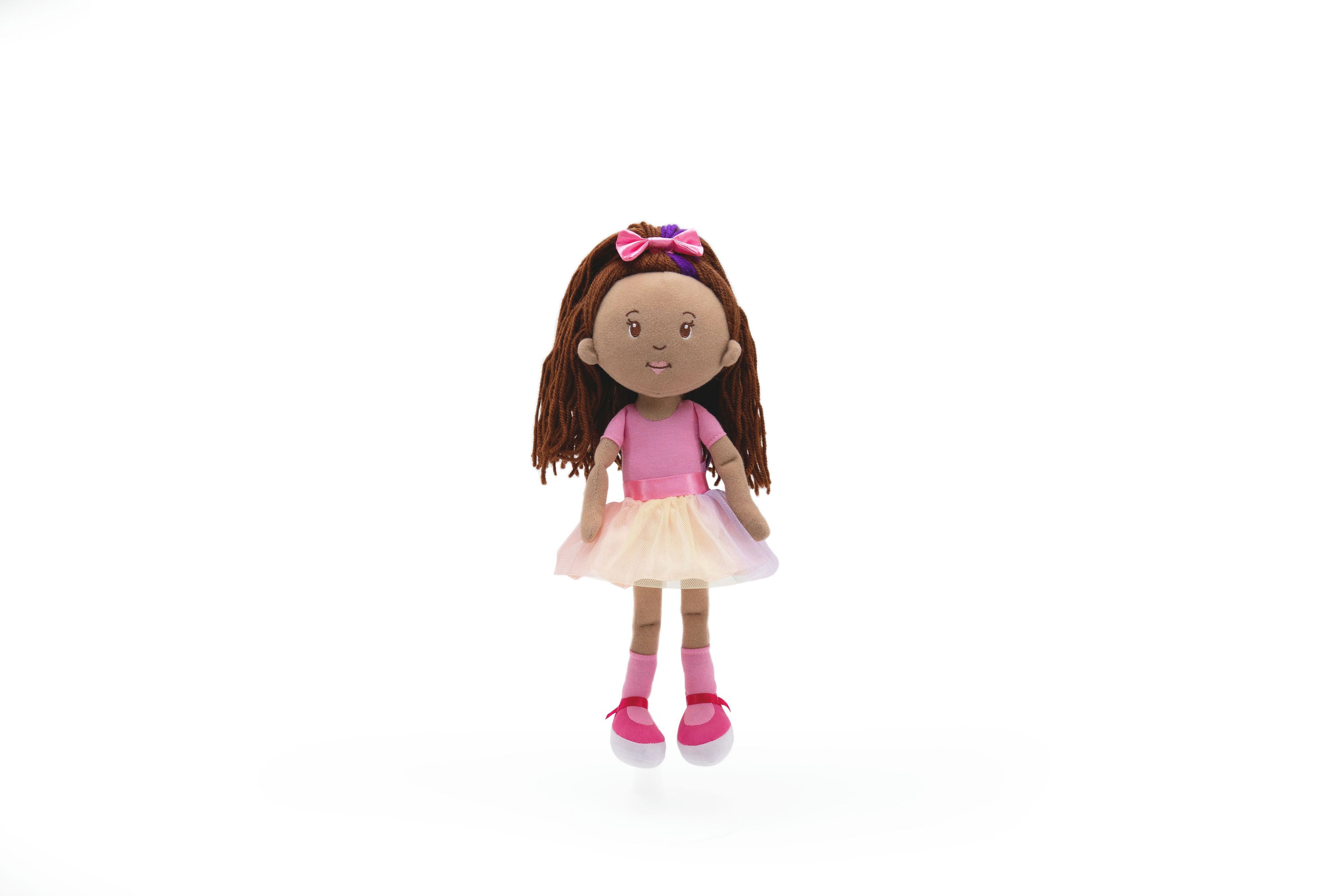 Doll with brown hair, pink top, and beige skirt on a white background
