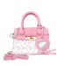 A pink handbag with a textured pink faux leather top, a white patterned lower section, gold-tone hardware, a detachable pink shoulder strap, and a heart-shaped mirror charm.