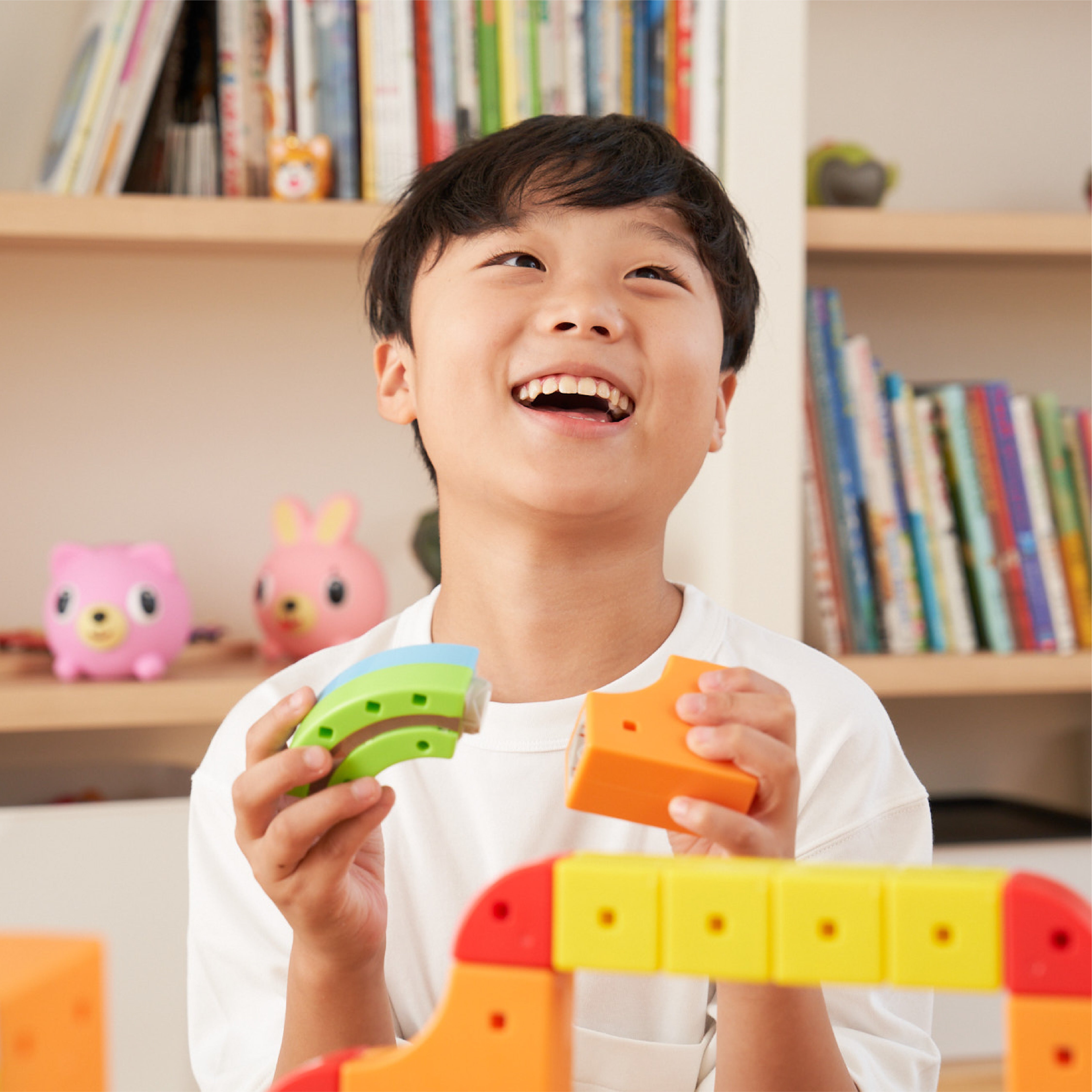 Child playing with colorful building blocks in a room with bookshelves.