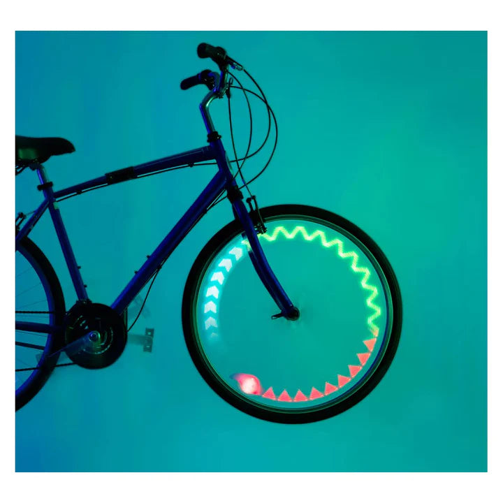 A bicycle wheel with illuminated LED graphics in green, white, and red, mounted on a dark blue bicycle against a solid teal background.