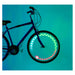 A bicycle wheel with illuminated LED graphics in green, white, and red, mounted on a dark blue bicycle against a solid teal background.