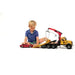 A young boy in a blue shirt sits on a yellow toy car carrier truck with a crane, playing on a white studio background.