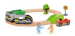 A wooden toy train set on a white background, featuring a curved wooden track with a gray and yellow BRIO train, green leaf-shaped hills, a small tree, a kangaroo sign, an orange toy truck, and two small animal figures.