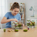 Person assembling a miniature garden kit with a box labeled 'Bonsai' in the background.