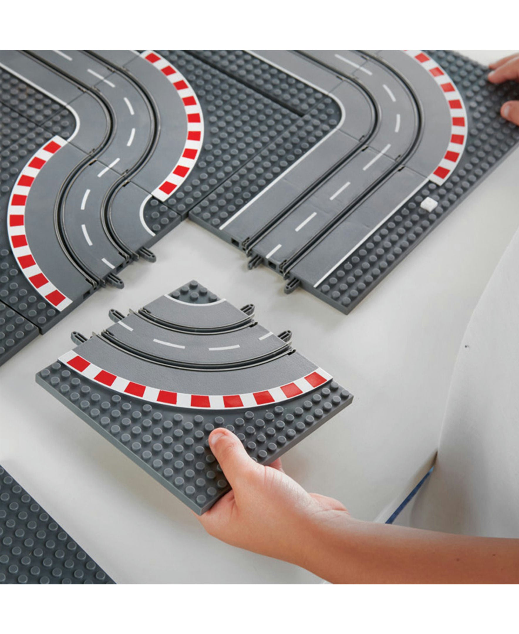 Toy race track set with curved and straight sections on a white surface.