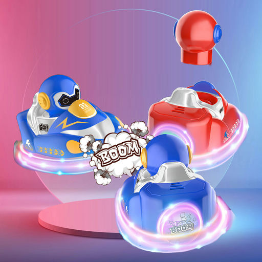 Three small toy spacecraft or ride-on vehicles shown in a stylized studio render: one blue with a cartoon duck face, one red with a helmet-like top, and one blue viewed from the back with glowing pink light effects. The scene has a pink-to-blue gradient background and comic-style 'BOOM' clouds.