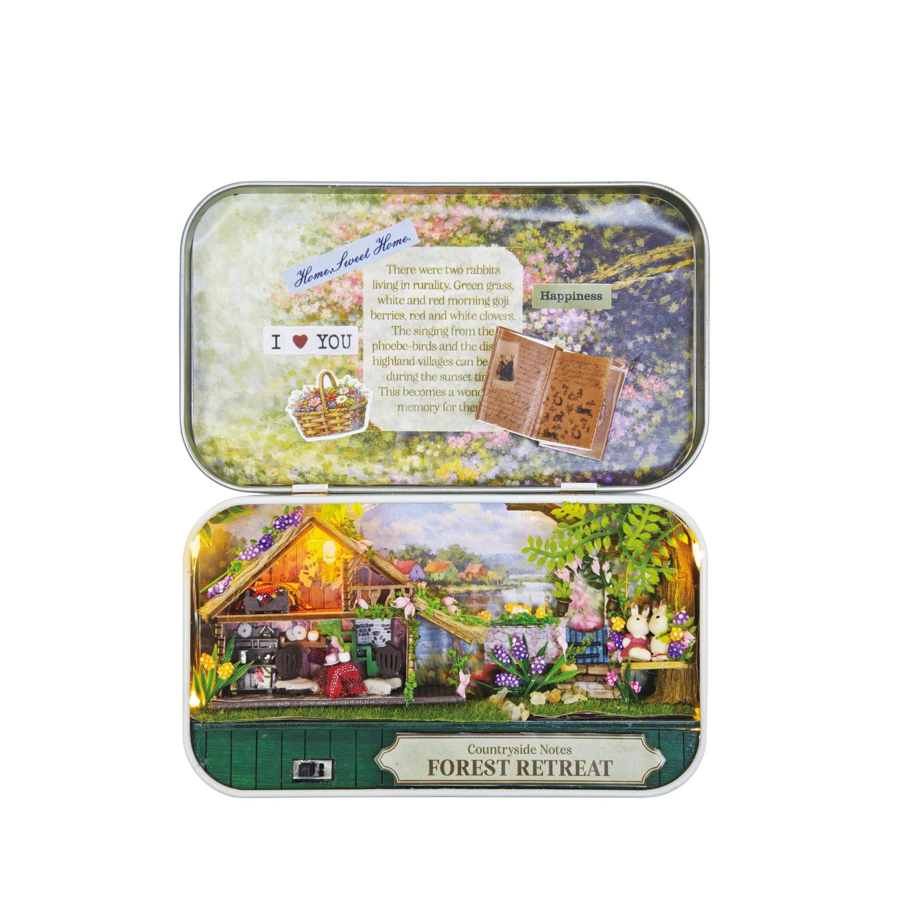 A rectangular metal tin shown from two sides on a plain white background. The top side features a pastel floral collage with text and small illustrations, while the bottom side shows a detailed miniature forest cottage scene with flowers, trees, and a sign reading 'Countryside Nest FOREST RETREAT'.