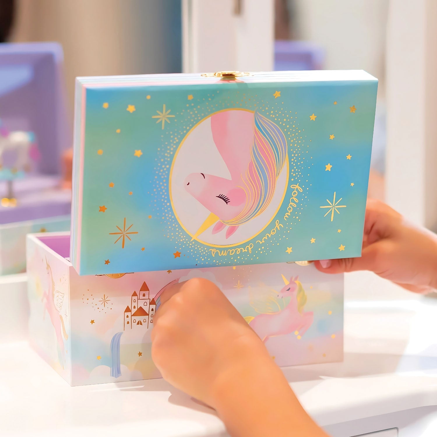 Colorful unicorn-themed jewelry box held by a hand with a blurred background