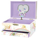 A decorative open music box with a lavender interior and unicorn-themed exterior. The front drawer is printed with pastel rainbow clouds, gold stars, a castle, and the words 'be magical.