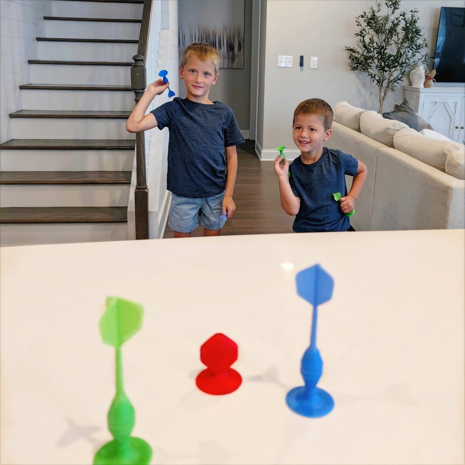 Two children playing with colorful plastic toys on a table in a living room.