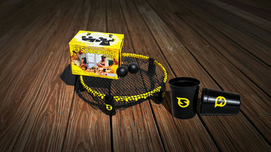 A set of Seliopang fishing nets and cups displayed on a dark wooden plank surface. The set includes a yellow and black net with two black fishing balls and a yellow brand box, alongside two black cups with yellow logos.