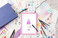 Artistic illustrations of fashion and accessories on a surface with drawing tools.