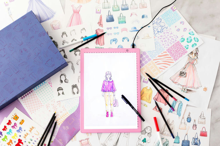 Artistic illustrations of fashion and accessories on a surface with drawing tools.