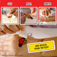 A close-up of a person peeling a red and yellow strawberry temporary tattoo from a skin patch with a white adhesive remover, accompanied by instructional panels showing how to cut, peel, and press the tattoo.