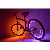 A bicycle with illuminated LED wheel lights glowing in orange and purple against a dark studio background.